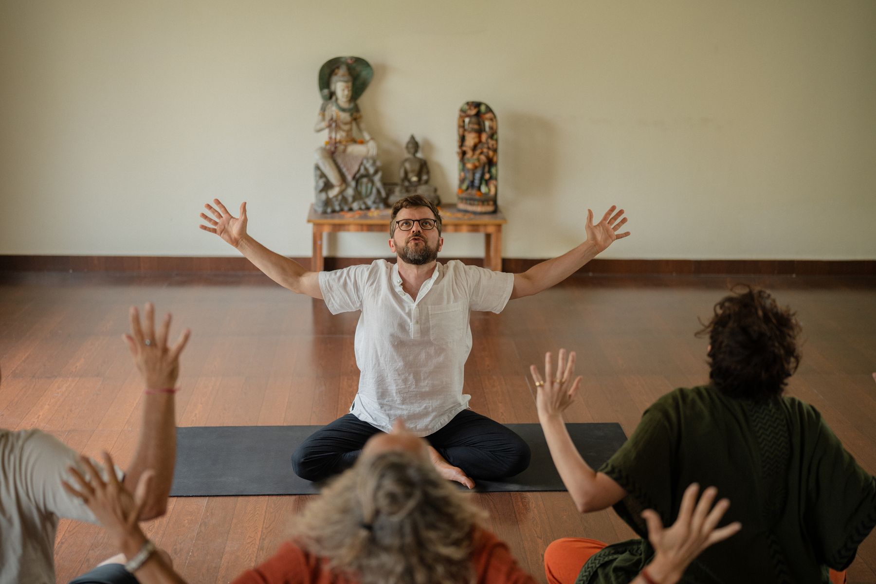 Hannes Wartmann sitzt im Schneidersitz vor der Gruppe, Arme geöffnet, Kundalini Kriya Yoga in Winterthur